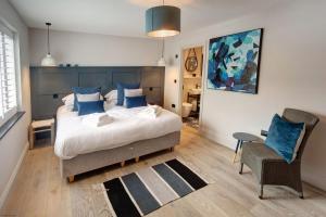 um quarto com uma cama com almofadas azuis e uma cadeira em Seaside House em Beadnell