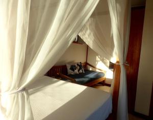 a bedroom with a white canopy bed with a couch at Luar do Leão Bungalow in Barra Grande +64 photos