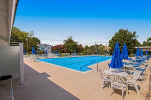 a swimming pool with chairs and blue umbrellas at Villas of Bethany West - 792B Salt Pond Circle in Bethany Beach