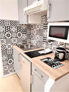a kitchen with a black and white tiled wall at joli studio dans maison niçoise in Nice