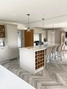 a kitchen with white cabinets and a counter with chairs at Boundary Farm in Middleton