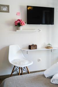 a room with a white chair and a tv on a wall at Rooms Anna in Milna