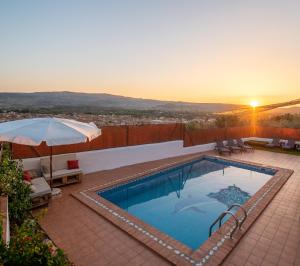 a swimming pool with a sunset in the background at Paraíso Villa de Granada in Dúrcal