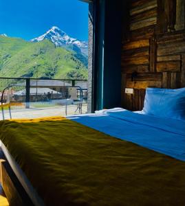 a bedroom with a bed with a view of a mountain at Hotel Misty Mountain in Kazbegi