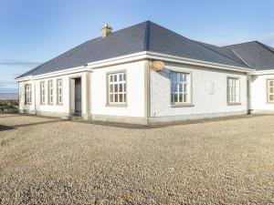 a white house on a gravel driveway at Tighe Carra in Ballygarries
