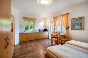 ein Schlafzimmer mit einem Bett und einem Schreibtisch sowie eine Küche in der Unterkunft Weingut Lieselehof Apt Vitis in Kaltern