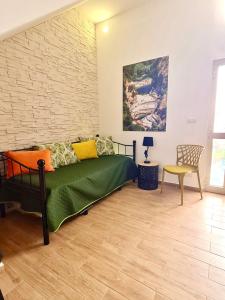 - une chambre avec un lit vert dans une pièce dotée d'un mur en briques dans l'établissement Strada Mastra Casa Vacanze, à Augusta