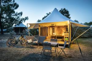 uma tenda com cadeiras, uma mesa e uma bicicleta em Huttopia Ars-en-Ré em Ars-en-Ré