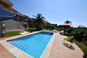 a swimming pool with an umbrella next to a house at Appartement & Spa - Panoramic Olivars in Pau