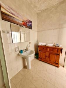 La salle de bains blanche est pourvue d'un lavabo et d'une armoire en bois. dans l'établissement Strada Mastra Casa Vacanze, à Augusta