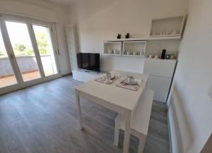 ein Wohnzimmer mit einem weißen Tisch und einem TV in der Unterkunft Casa al Lago Leone d'Oro in Peschiera del Garda