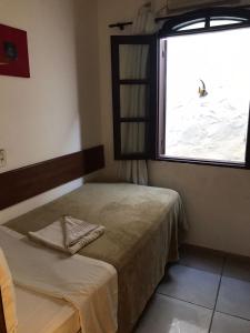 a small bedroom with a bed and a window at Pousada do Marinho in Búzios
