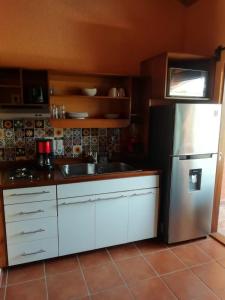 La cuisine est équipée de placards blancs et d'un réfrigérateur en acier inoxydable. dans l'établissement Mountain View Lofts Guayabitos, à Rincon de Guayabitos