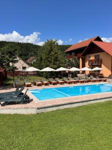 une grande piscine avec des chaises longues et des parasols dans l'établissement PENSIUNEA KELEMEN, à Praid