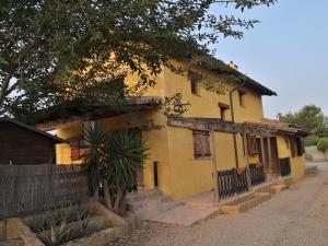 een oud geel huis met een boom ervoor bij La Casa Amarilla in Totana