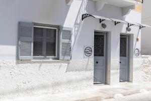 a white house with blue doors and windows at LUNA & TERRA APARTMENTS SYROS in Ermoupoli