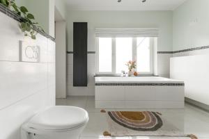 baño con aseo, bañera y ventana en Vakantiewoning 't Hovenshuis en Kinrooi