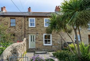 a brick house with a palm tree in front of it at The Boy's Cottage in Portreath