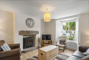 a living room with a fireplace and a clock on the wall at The Boy's Cottage in Portreath