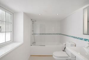een witte badkamer met toilet en ligbad bij The Boy's Cottage in Portreath +22 foto's