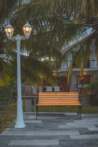 a bench next to a light pole and a palm tree at Between 2 waters Villa, free rental car offered. in Tamarin