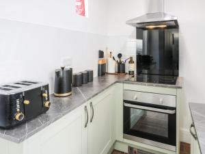 a kitchen with a counter with a stove and a microwave at Jasmine Villa in Llandudno