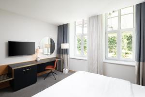 a hotel room with a bed and a desk with a television at K+K Hotel Fenix in Prague