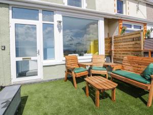 a patio with two benches and a table and chairs at Jasmine Villa in Llandudno