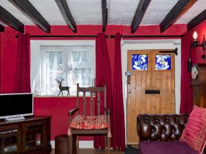 a room with a red wall with a chair and a window at Pass the Keys Cosy Cottage with Fireplace in Bridgwater