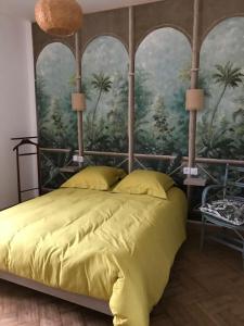 une chambre avec un lit jaune avec une peinture de palmiers dans l'établissement Superbe T2 dans un parc arboré, à Lamalou-les-Bains