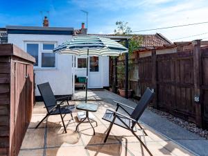 a patio with two chairs and an umbrella at Pass the Keys Cosy Cottage with Fireplace in Bridgwater