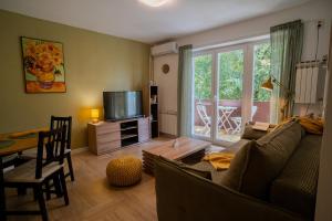 a living room with a couch and a table and a television at Apartman Terra centar, free parking in Osijek