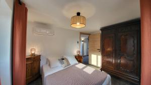 カルヴィにあるEntre ciel et mer dans la Citadelleのベッドルーム1室(ベッド1台付)、大きな木製キャビネットが備わります。