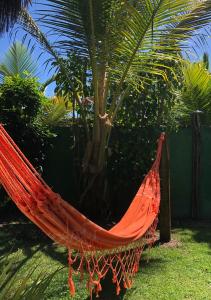 uma rede de descanso laranja num jardim com uma palmeira em Luar do Leão Bungalow em Barra Grande