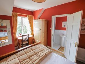 Schlafzimmer mit roten Wänden, einem Bett und einem Schreibtisch in der Unterkunft The White House in Drumshanbo
