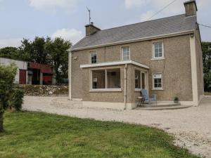 a brick house with a chair in front of it at Mulroy Cottage in Glinsk