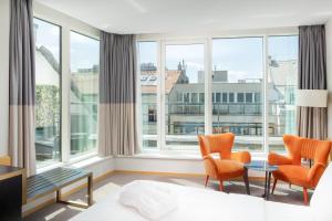a hotel room with a bed and chairs and large windows at K+K Hotel Fenix in Prague