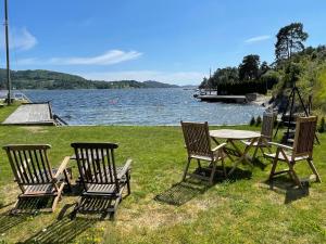 una mesa de picnic y 4 sillas junto a un lago en Leilighet ved sjøen med strand, en Porsgrunn