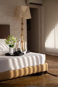Una cama blanca con un jarrón de flores. en Hotel Canaleta Heras en Espolla