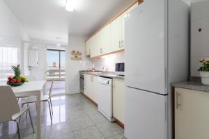 a kitchen with a white refrigerator and a table at Cozy Sunny Flat w/ Terrace - São João in Porto