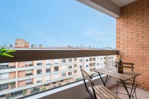 a balcony with a wooden table and chairs and a building at Cozy Sunny Flat w/ Terrace - São João in Porto