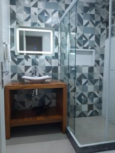 een badkamer met een wastafel en een douche met een spiegel bij Estúdio na quadra da praia in Rio de Janeiro