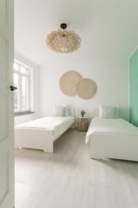 Habitación blanca con 2 camas y lámpara de araña. en Vakantiewoning 't Hovenshuis en Kinrooi