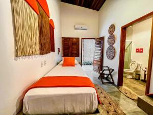 a bedroom with a bed with an orange pillow at Pousada Roots - D3 Experience - Préa, CE in Prea