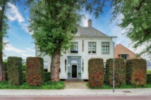 a white house with a large hedge in front of it at Amsterdam Mansion - The Studio in Oostzaan