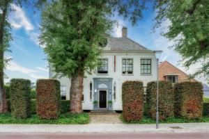 een wit huis met een grote heg ervoor bij Amsterdam Mansion - The Studio in Oostzaan