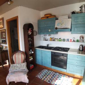 タオルミーナにあるCasa Vacanze Scacciapensieriのキッチン(青いキャビネット、シンク、コンロ付)