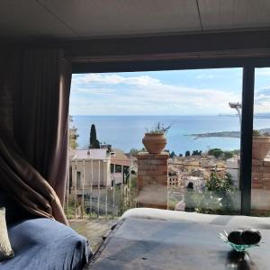タオルミーナにあるCasa Vacanze Scacciapensieriのベッドルームの窓から海の景色を望めます。