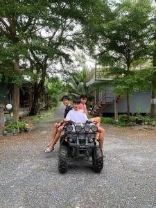 three people sitting on a four wheeler in a driveway at COCO HOME Homestay(โคโค่โฮม) in Ban Mo Kaeng Taek