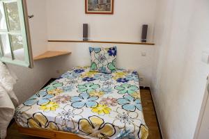 a small bedroom with a bed with a floral comforter at le gite du vial in Revest-les-Roches